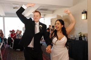 People dancing and celebrating at a wedding reception with raised arms and joyful expressions.