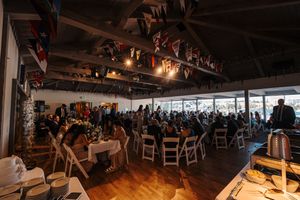Panoramic view of a wedding venue with wooden beams, hanging flags and natural lighting.