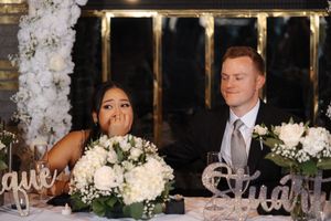 A formal wedding reception banquet table decorated with white floral centerpieces and elegant place settings.