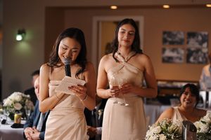 Wedding party attendants in blush pink dresses check their phones together during a celebration.