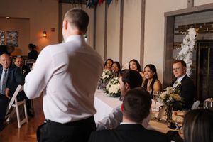 Wedding photographer captures candid reception moments with crew of cameras and photographic equipment at indoor venue.