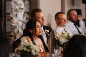Wedding guests gather at an elegant reception venue decorated with orchid centerpieces and glowing candles.