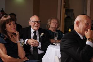 People in formal attire socialize at an elegant evening event with ambient lighting and glassware on tables.