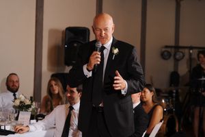 Wedding guests seated at tables during a reception in an elegant indoor venue.