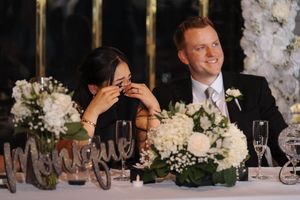 Wedding reception candid moment showing laughter and celebration with white floral centerpieces and champagne glasses.