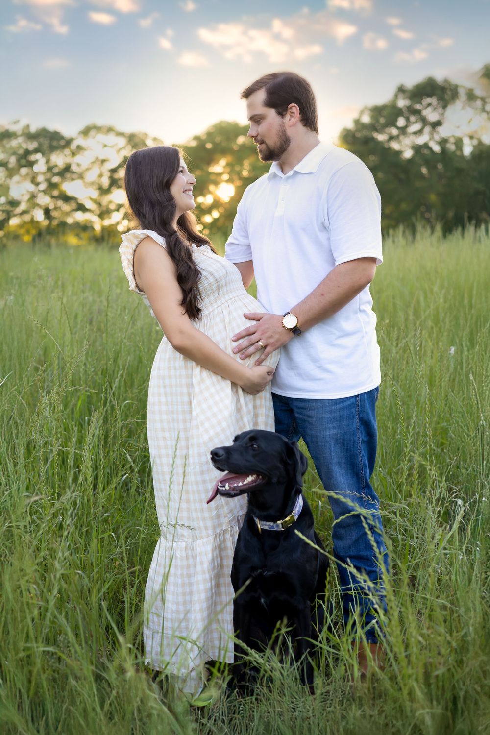 Couple looking at each other with dog during sunset during maternity session in Athens, GA