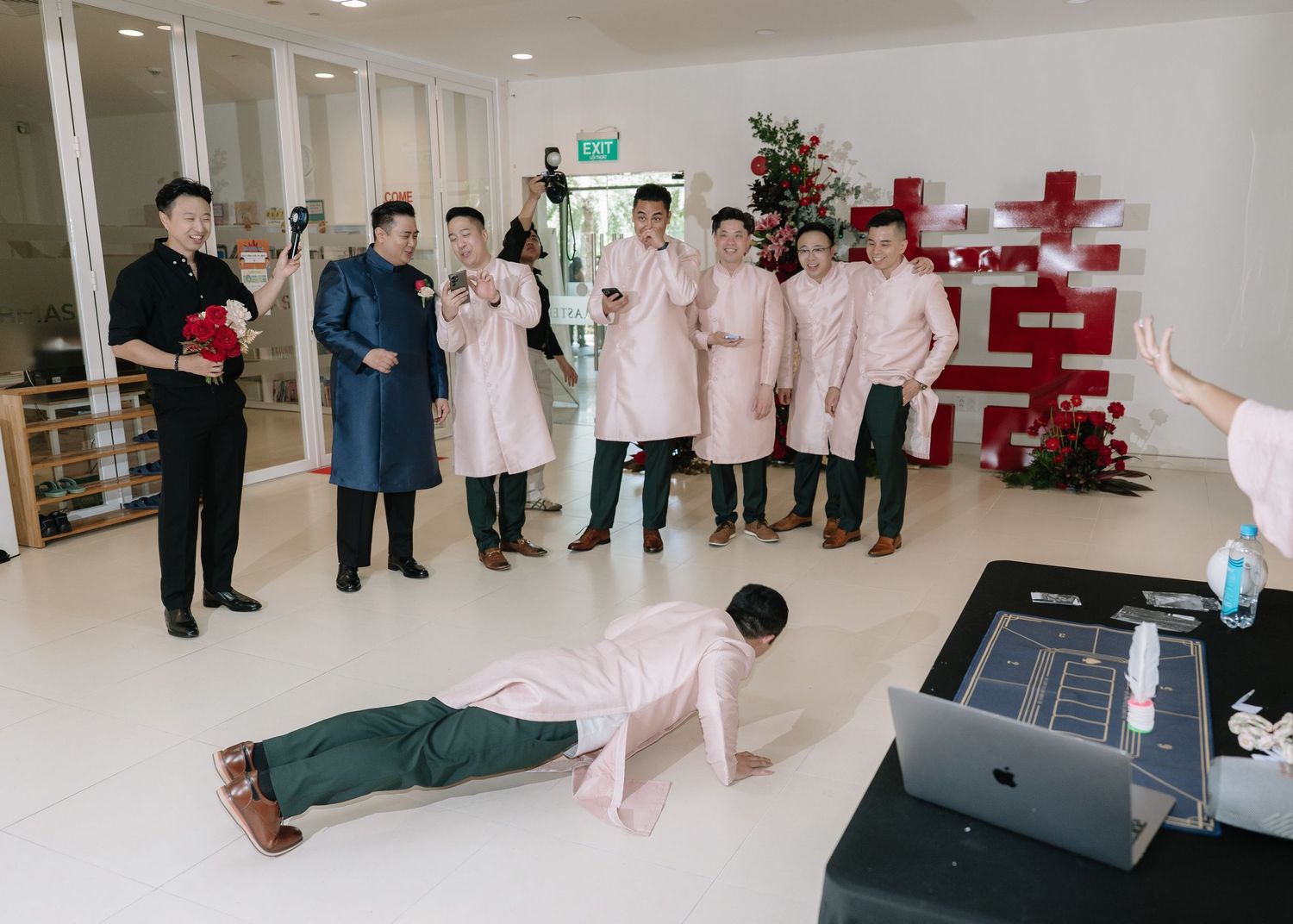 Groomsman does push-ups as wedding game challenge while guests laugh at Vietnamese ceremony.