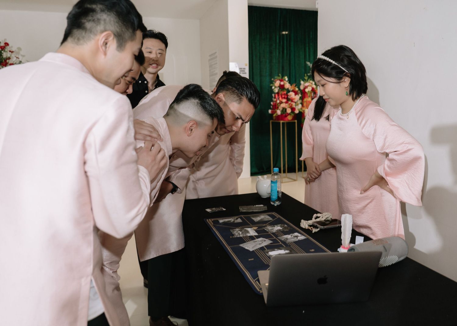 Wedding party members examine jewelry display on table at traditional Vietnamese engagement ceremony.