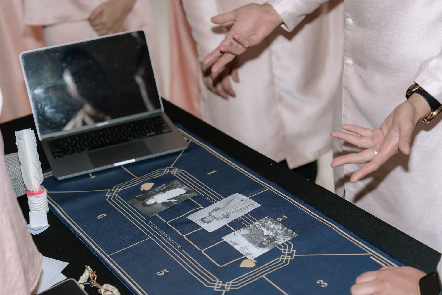 Close-up of a navy blue wedding game board with gold details, photos, and a laptop at a Vietnamese wedding.