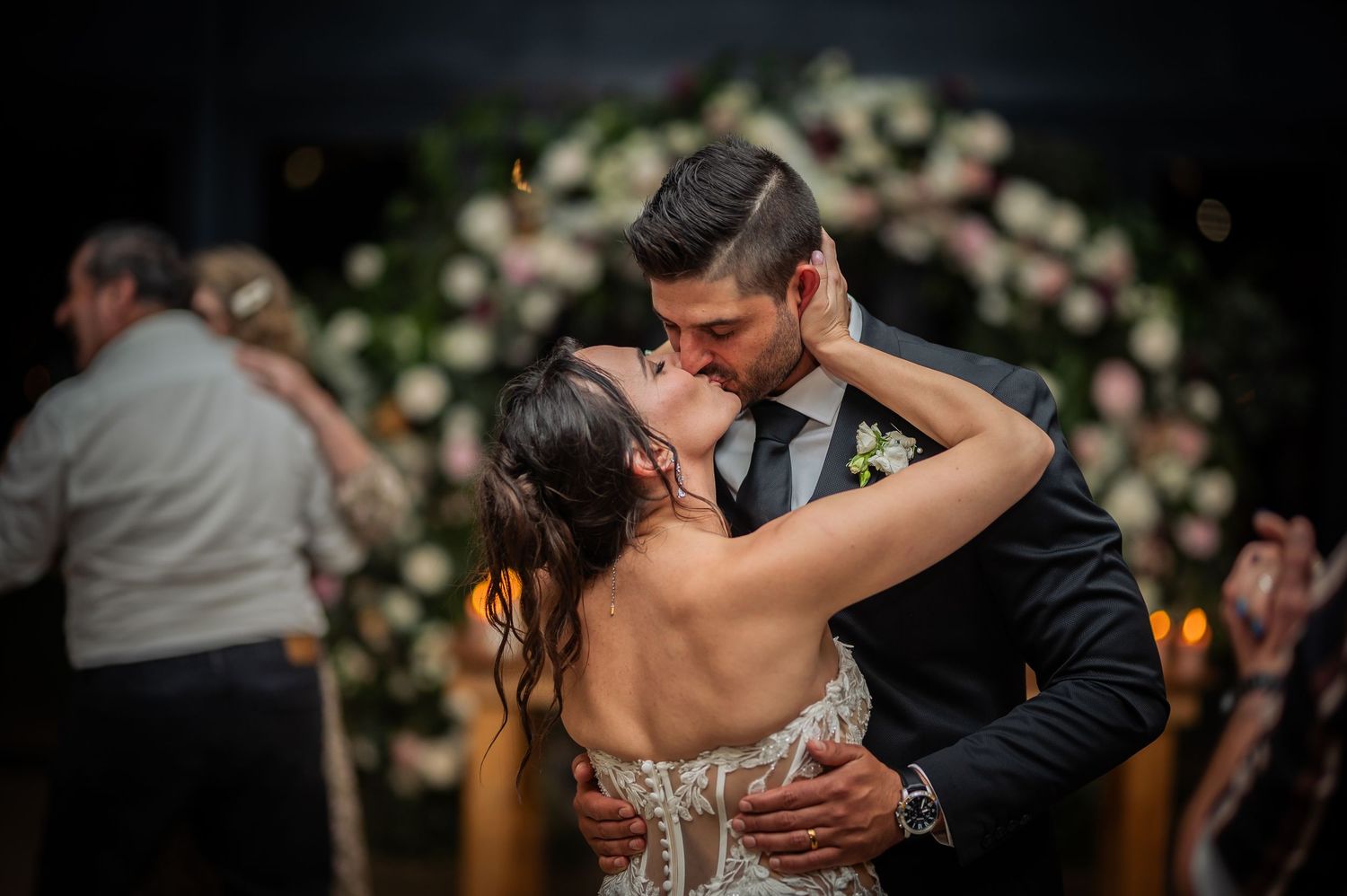 Romantic couple shares intimate dance moves during an elegant wedding reception with soft floral backdrop decorations.