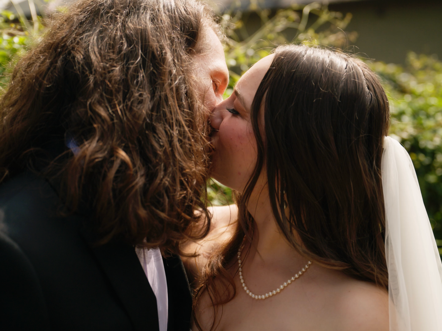 Romantic wedding couple sharing an intimate moment surrounded by greenery.