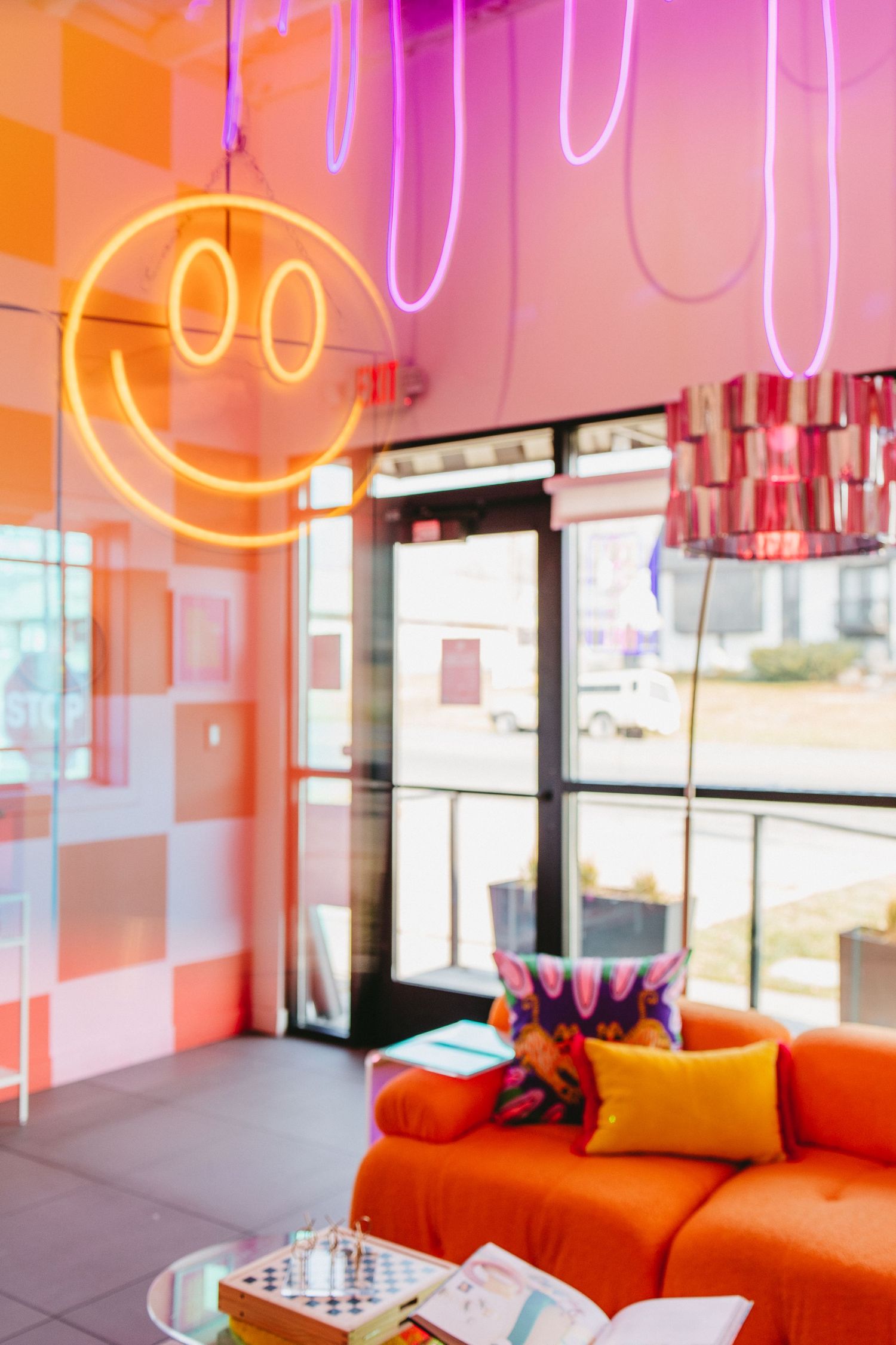 a fun, vibrant lounge with an orange couch, neon lights, and a smiley face neon sign