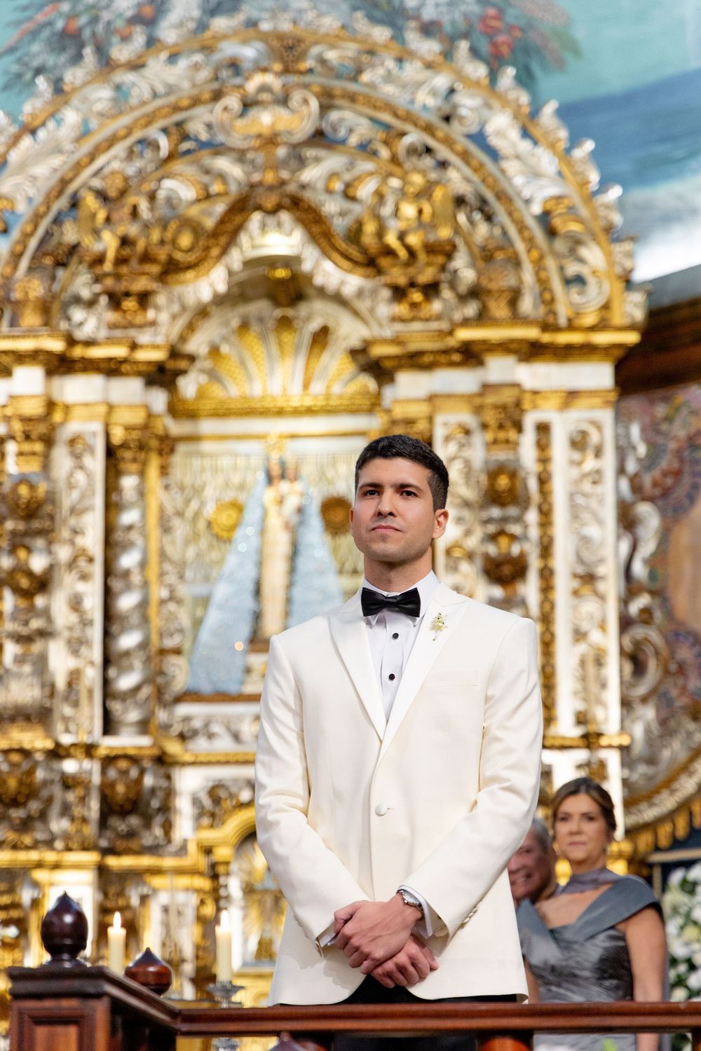 Ornate golden baroque altar or retablo with intricate decorative details serves as backdrop in formal event setting.