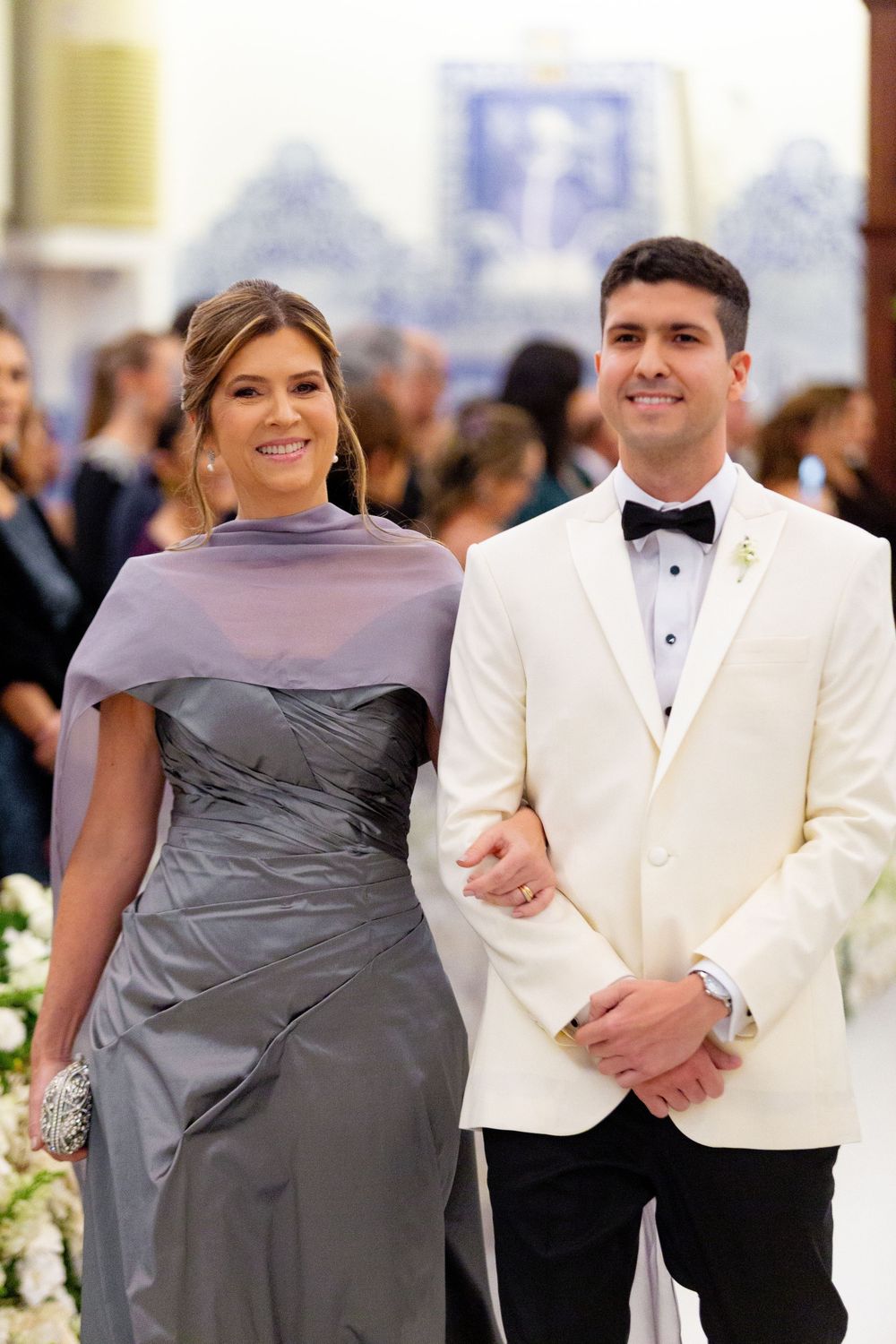 Wedding party members in gray dresses and white tuxedos stand together at an elegant formal reception.