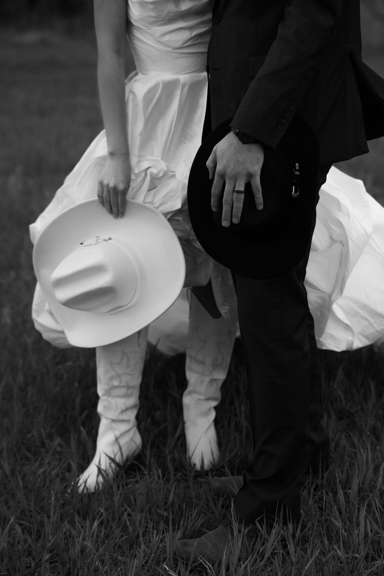 Black and white close-up of feet on grass with white formal attire and black dress shoes.
