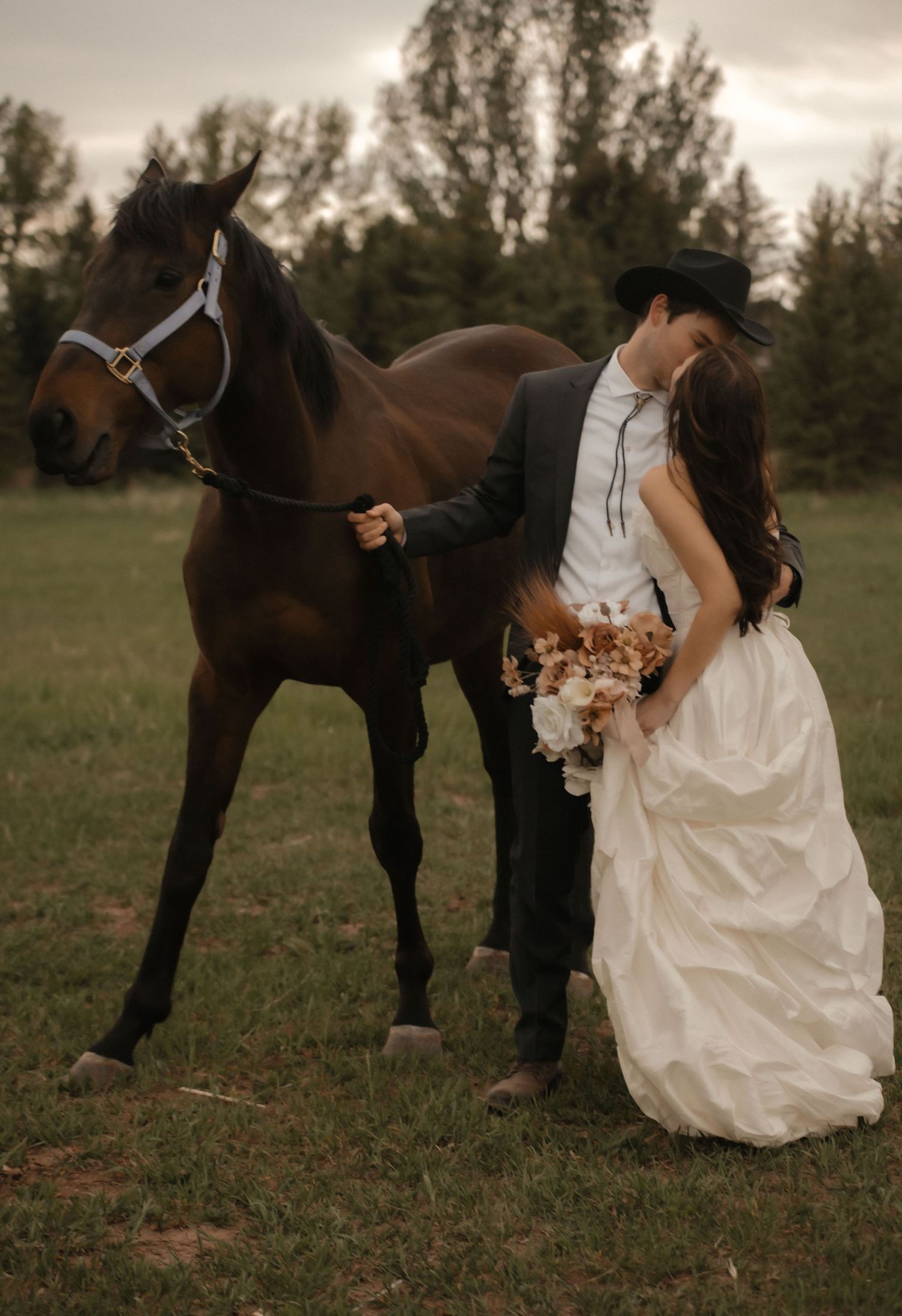 A series of photographs showing a bride in a white gown posing with a brown horse in a grassy field during sunset.
