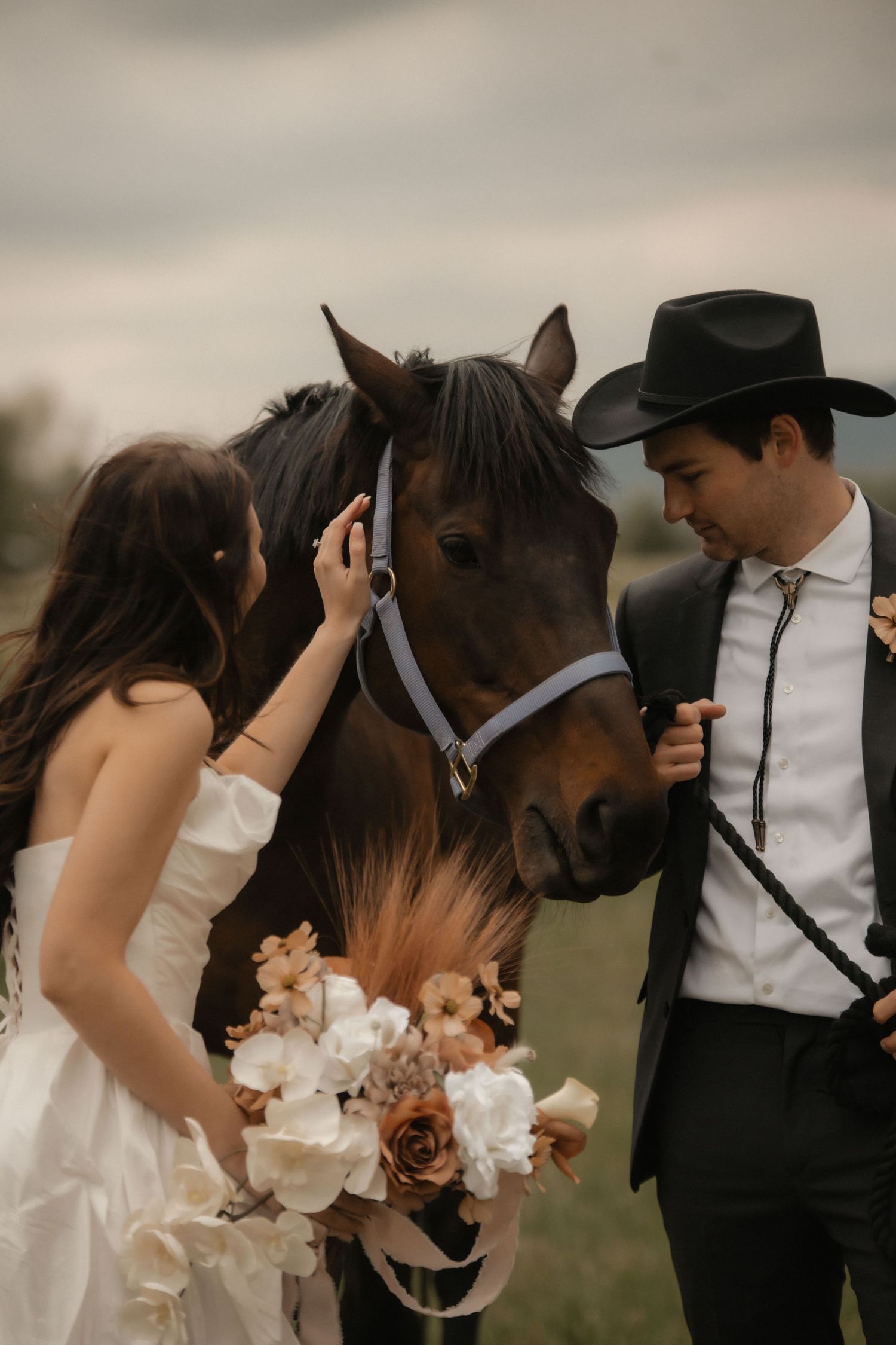 A romantic wedding couple shares intimate moments with their horse in a dreamy outdoor setting.