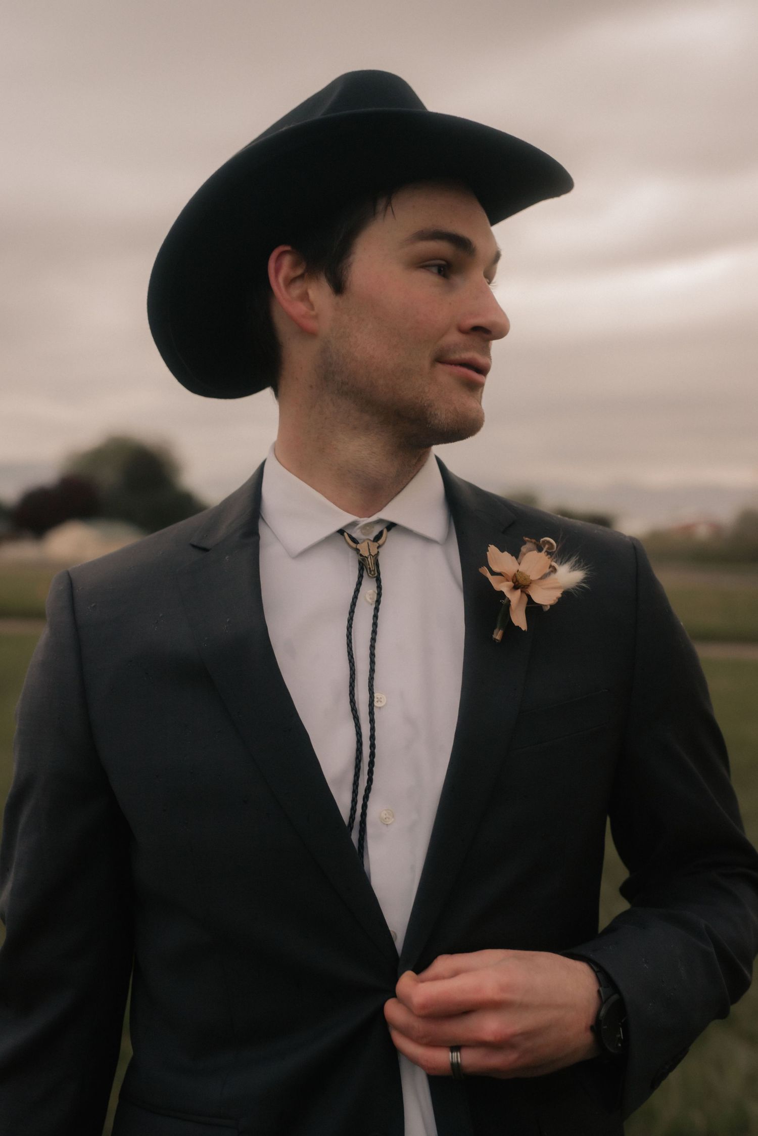 Close-up view of someone in a black cowboy hat and western formal wear with a bolo tie.