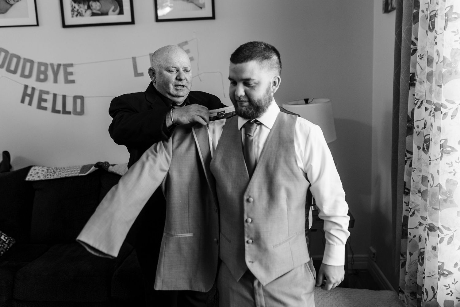A black and white candid photo shows a fun, joyful moment between two figures in a room with party decorations.
