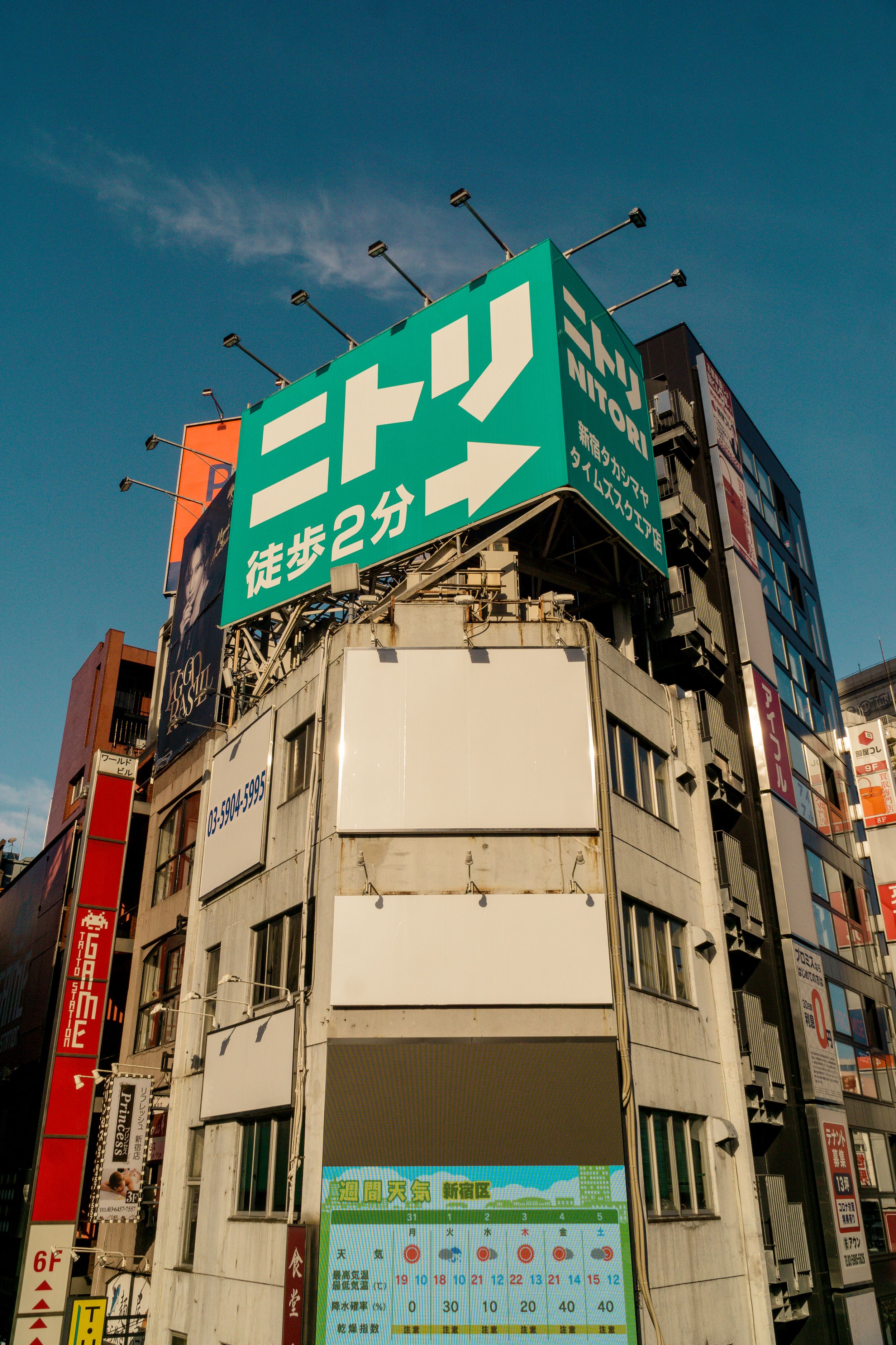Time lapse series showing changing directional signs on corner of building in Japanese urban area against blue sky.