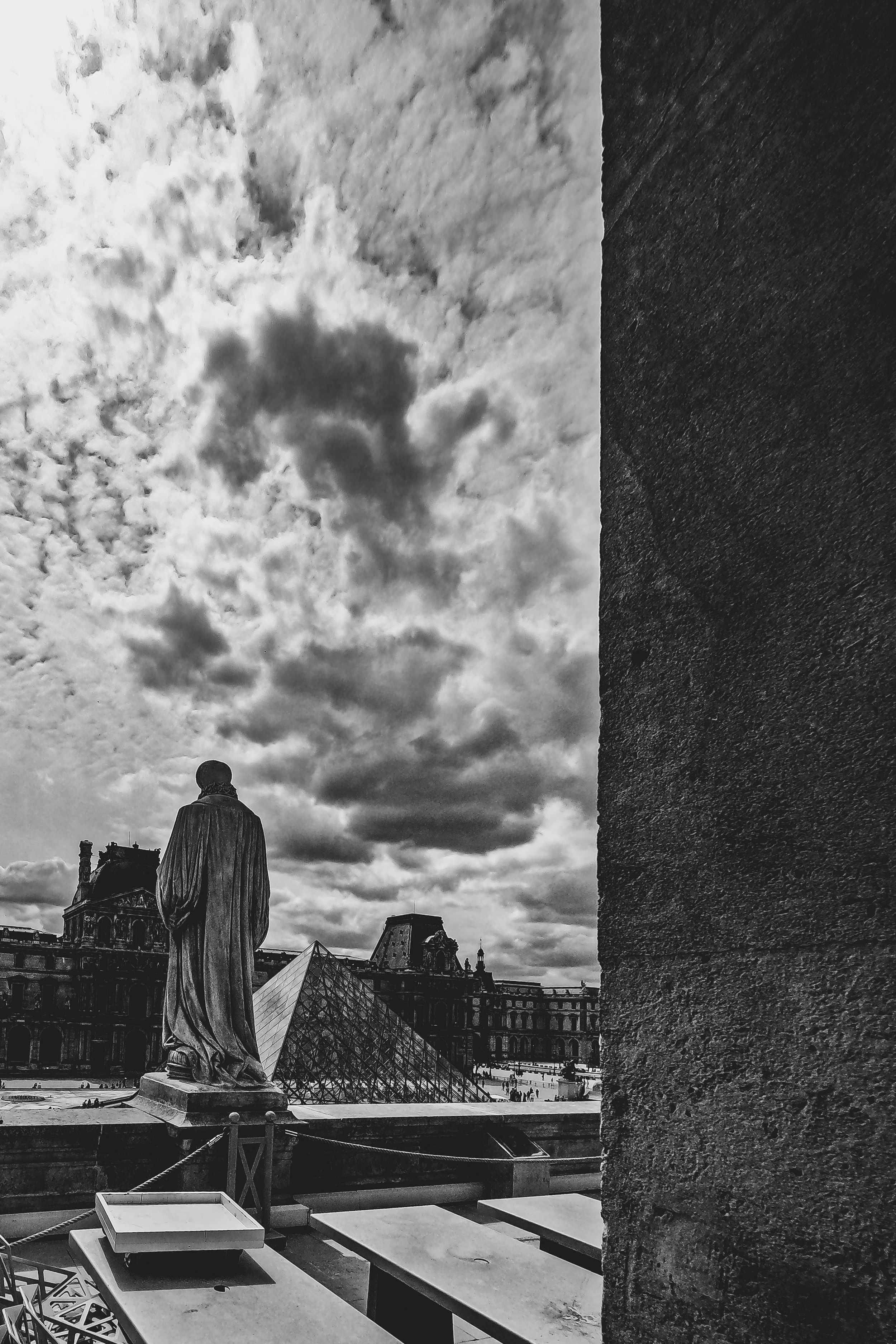 Dramatic black and white panoramic view of a cityscape with looming storm clouds overhead.