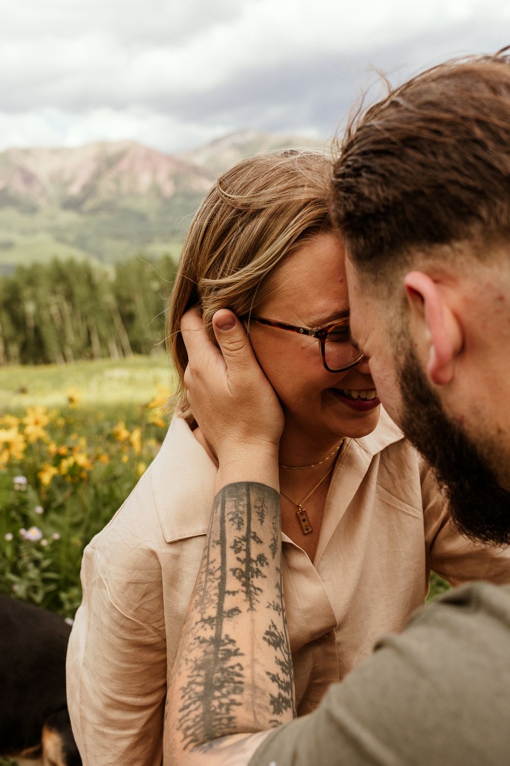 A couple shares intimate romantic moments surrounded by mountain wildflowers during a golden hour photoshoot.
