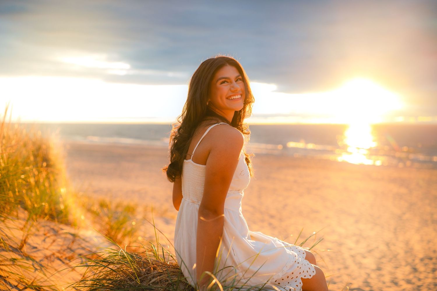 Scenic beach sunset photoshoot with warm golden light filtering through tall grass.