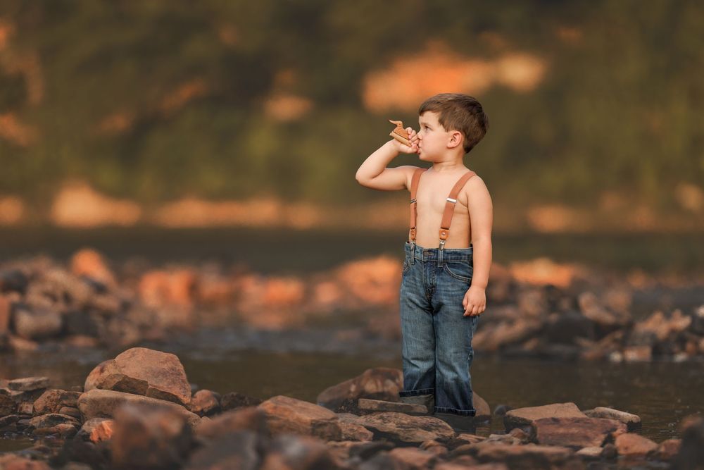 A figure stands barefoot in a stream among scattered rocks during golden hour sunlight.