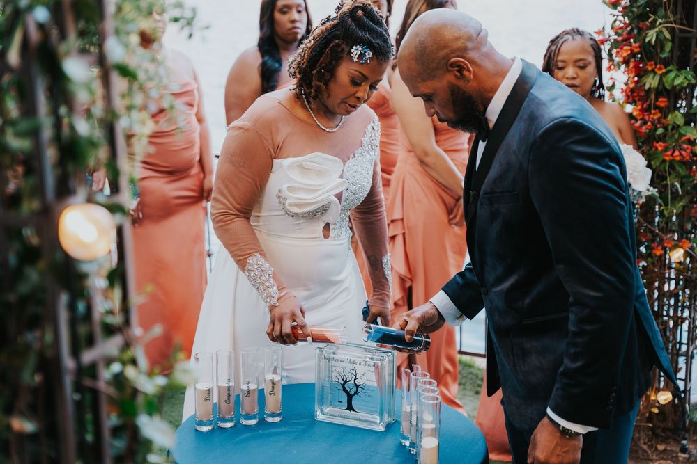 Couple participates in wedding sand ceremony pouring blue crystals during outdoor ceremony.