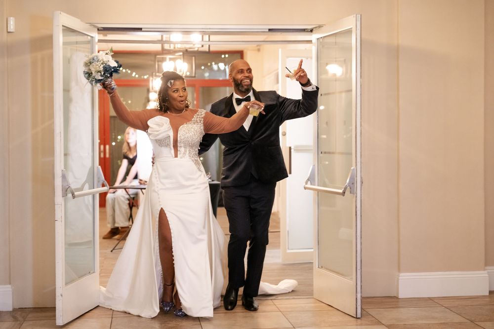 Wedding party dances through hotel corridor in a choreographed group celebration pose at a reception venue.