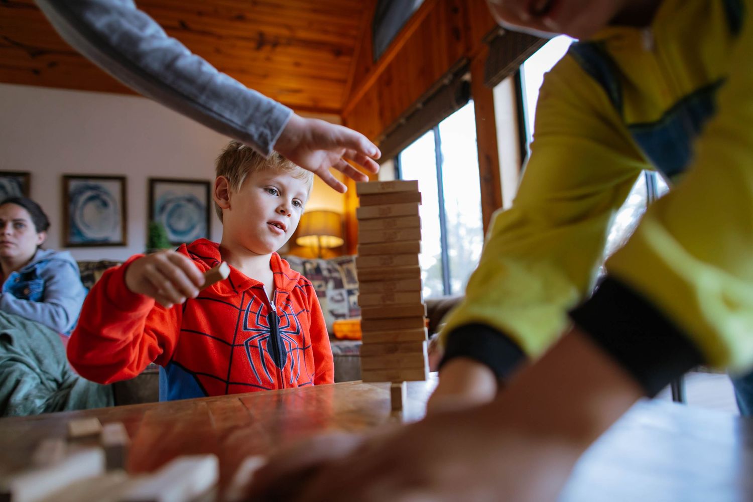A sequence of photos showing children at a wooden dining table playing and interacting with a board game.