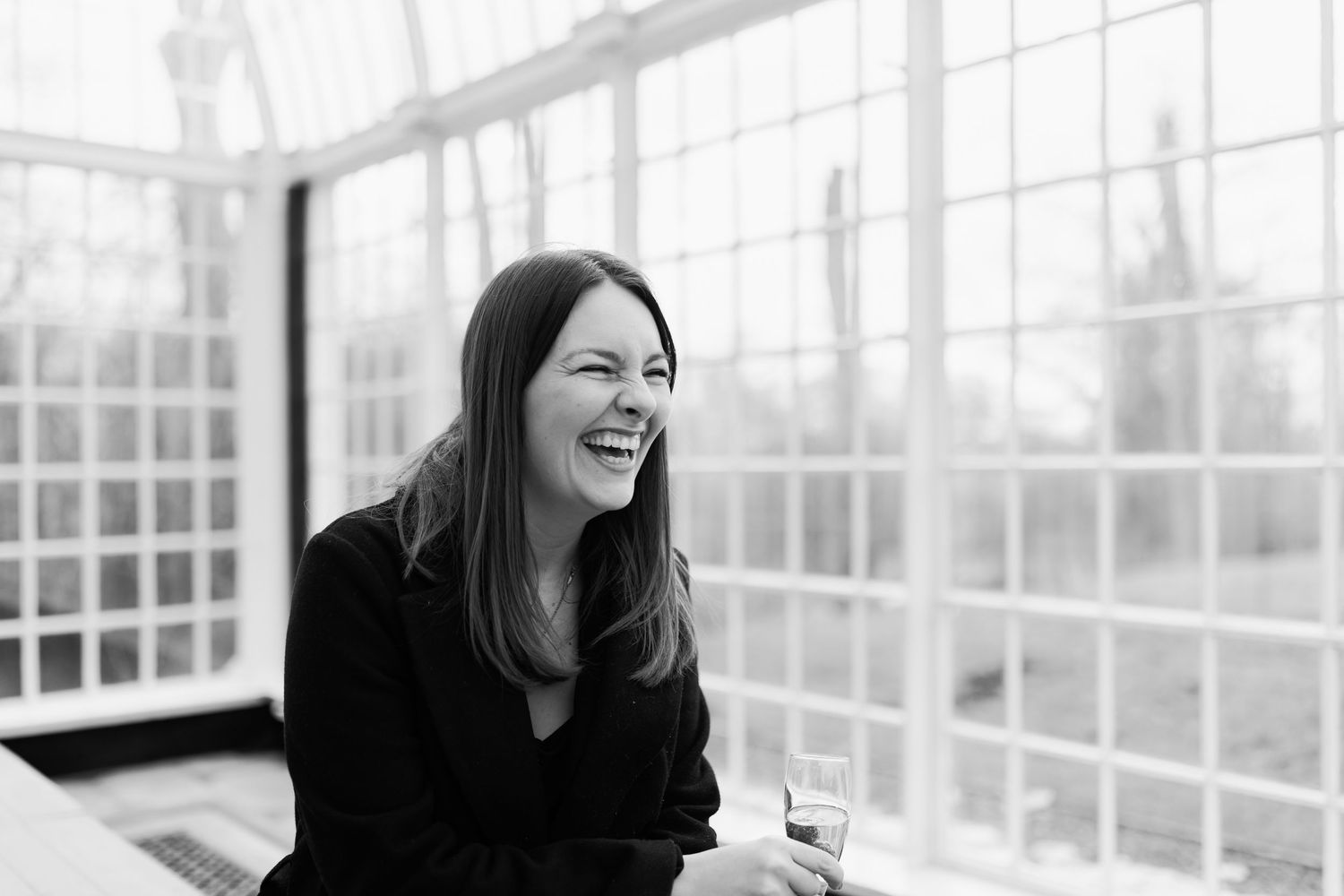 A series of black and white photos showing someone laughing and enjoying conversation in a bright sunlit room.