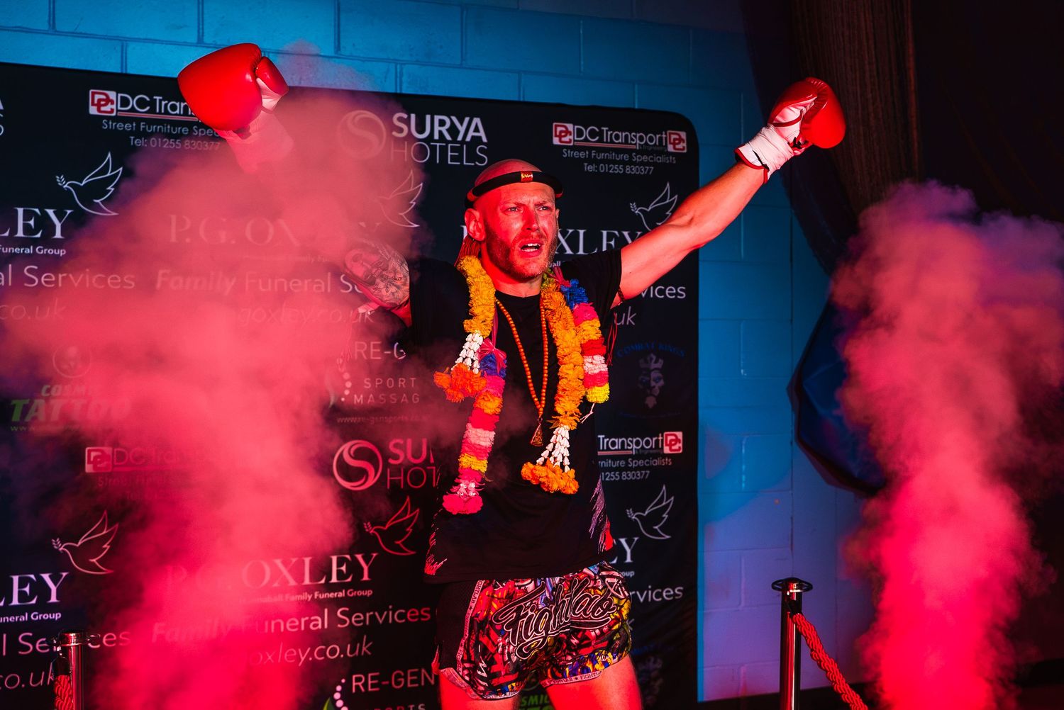 Boxer enters arena with red smoke cannons, wearing red gloves and colorful scarf, arms raised in triumph.