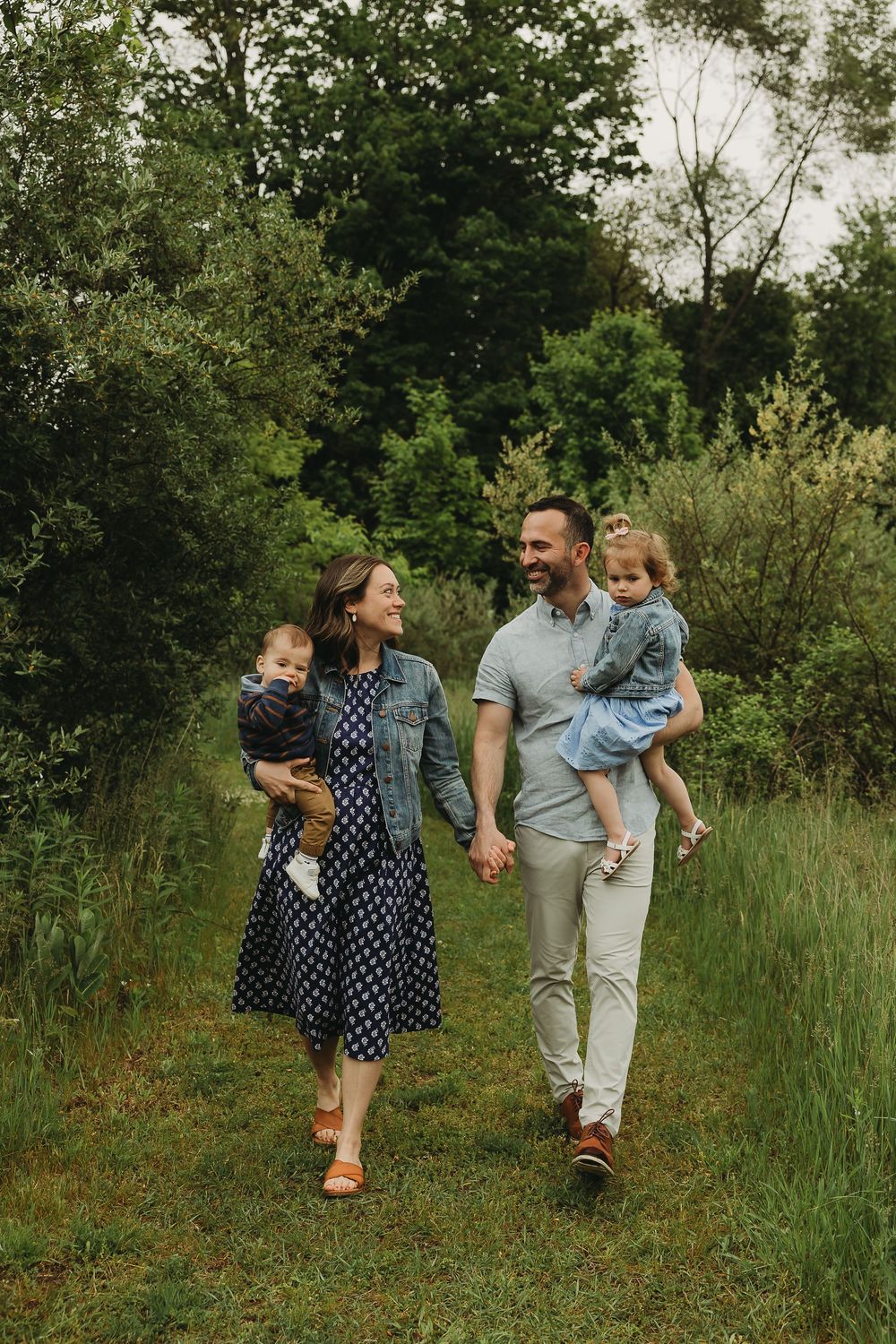 A joyful group walks together along a scenic grass path through lush green foliage on a summer day.
