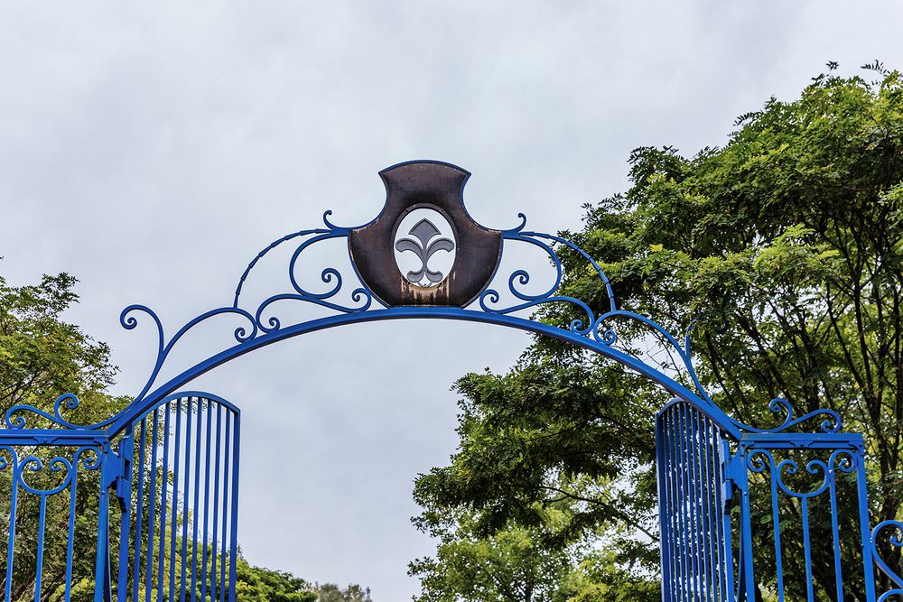 Ornate blue wrought iron gates with decorative arch detail against cloudy sky.