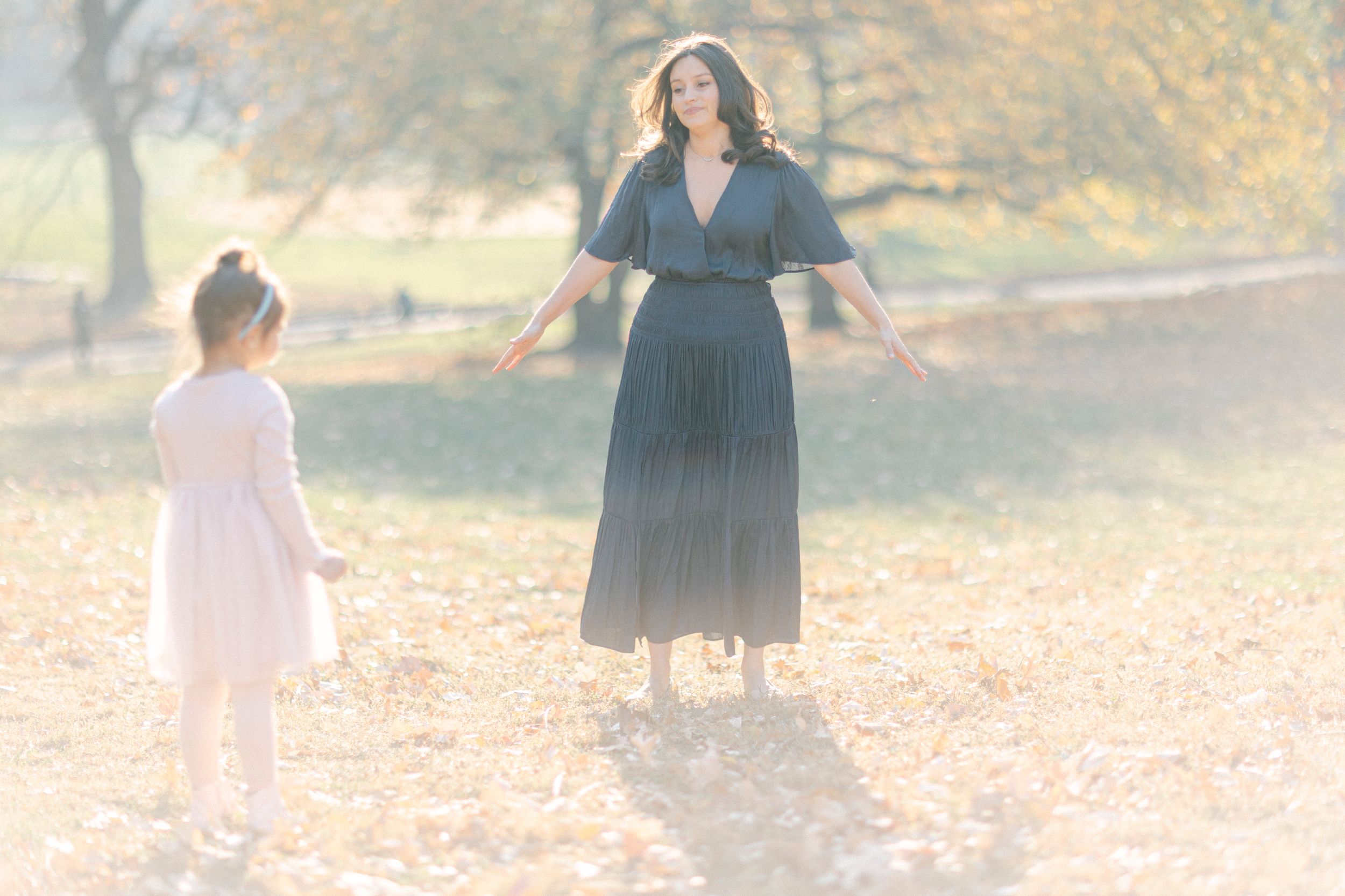 Two people enjoy a playful moment in an autumn park with golden lighting.