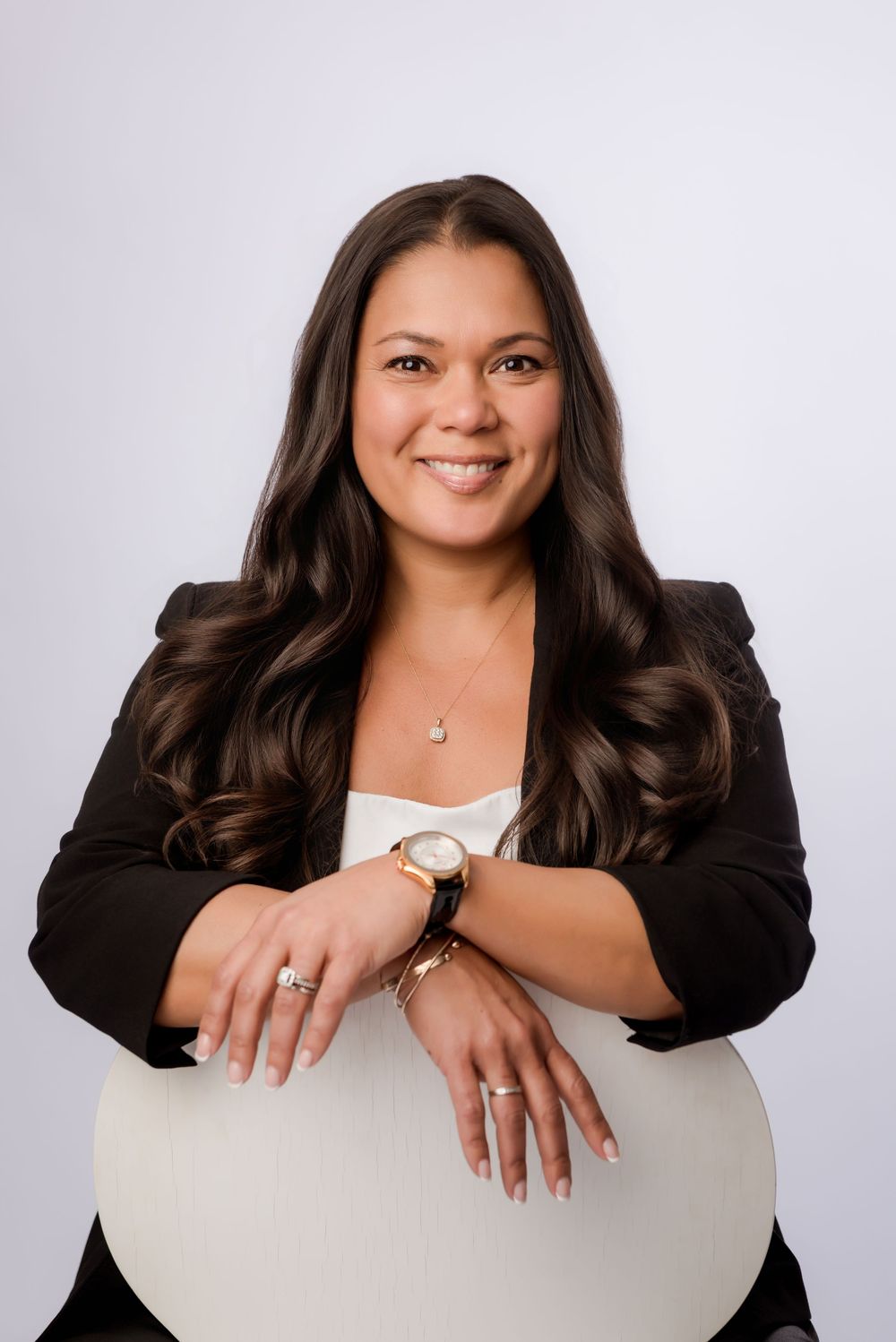 Professional headshots of a person in a black blazer smiling against a white background in various poses.