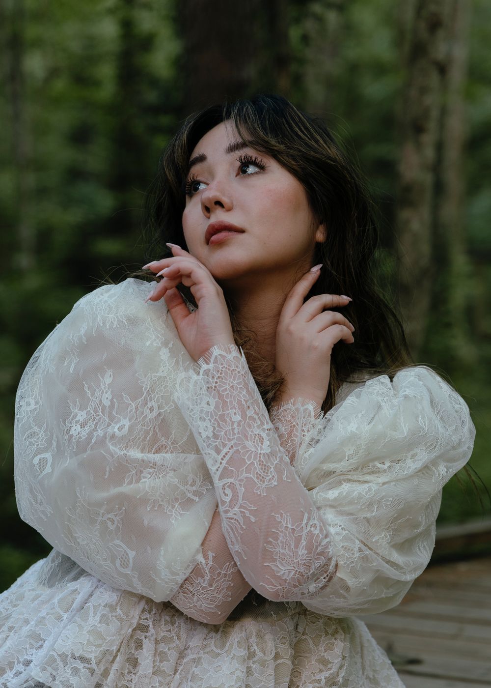 Model wearing white lacy dress, posing in the forest