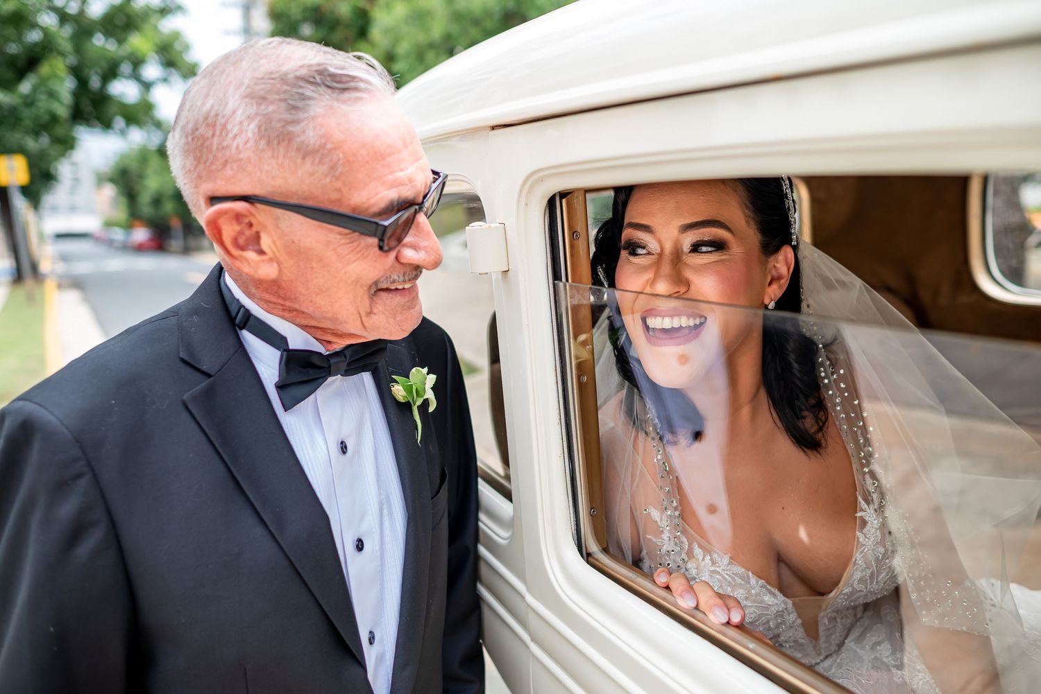 Sweet moment shared between two people by a classic white wedding car.