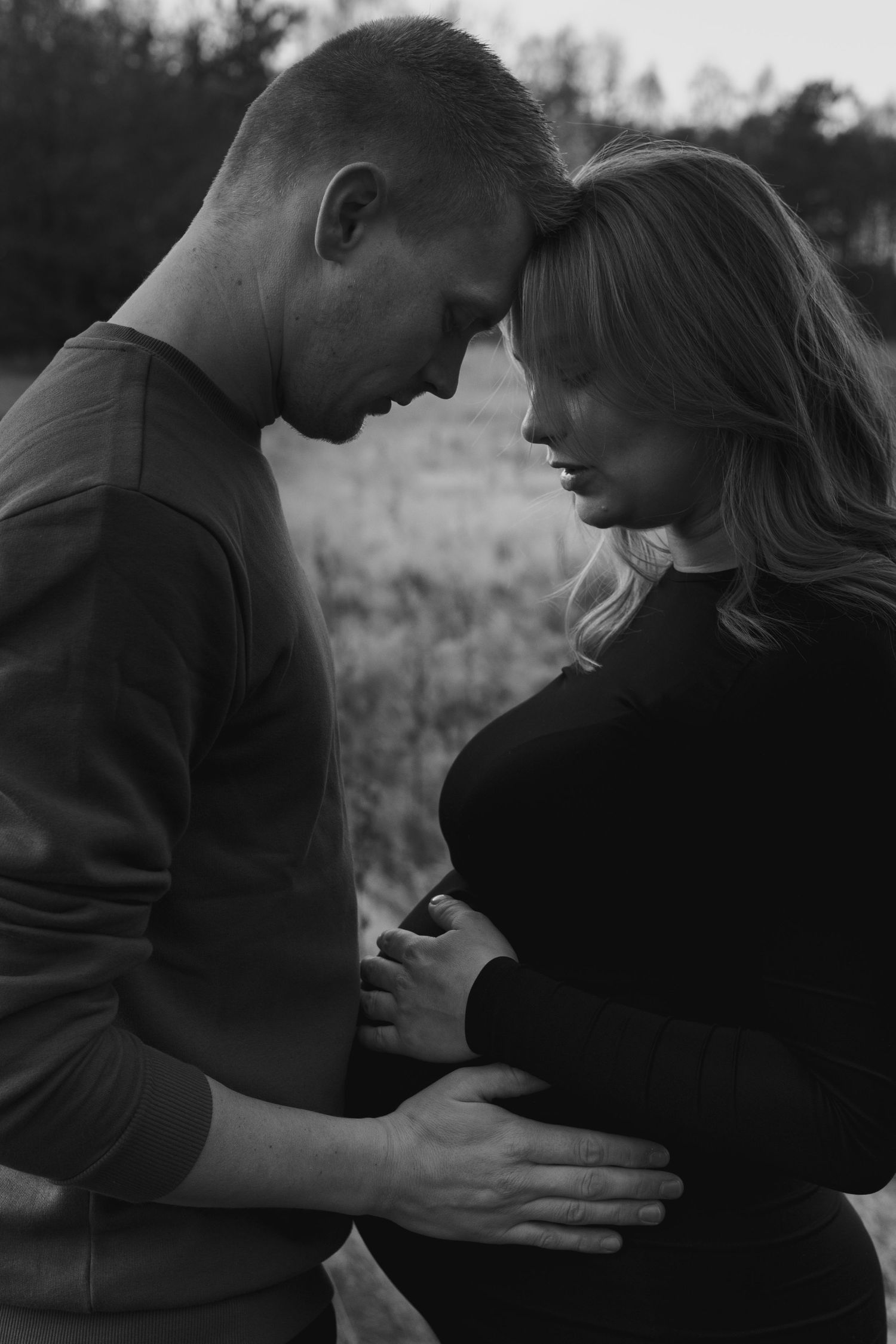 An intimate moment captured between a couple as they embrace in a rustic outdoor setting.