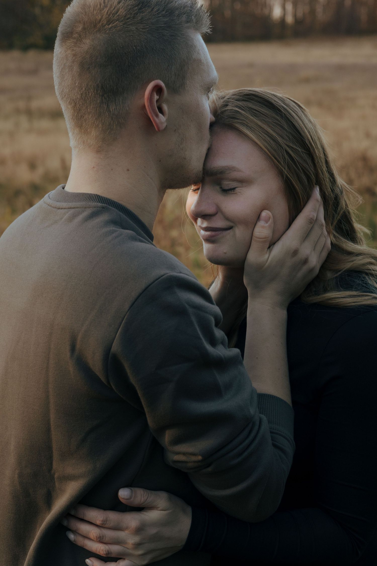 A tender embrace captured in warm autumn light as a couple shares an intimate moment outdoors.