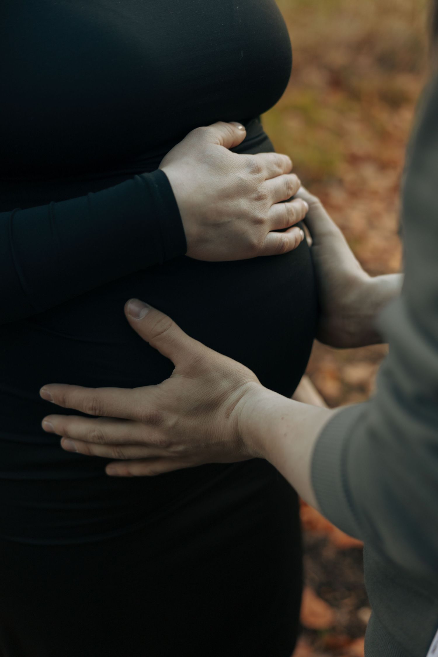 Close-up shot of hands tenderly placed on a pregnant belly.