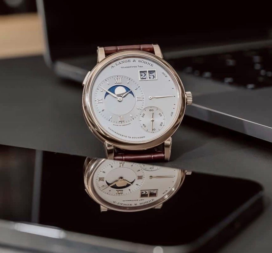 A stylish wristwatch with diamond bezel and orange textile strap photographed in warm lighting.