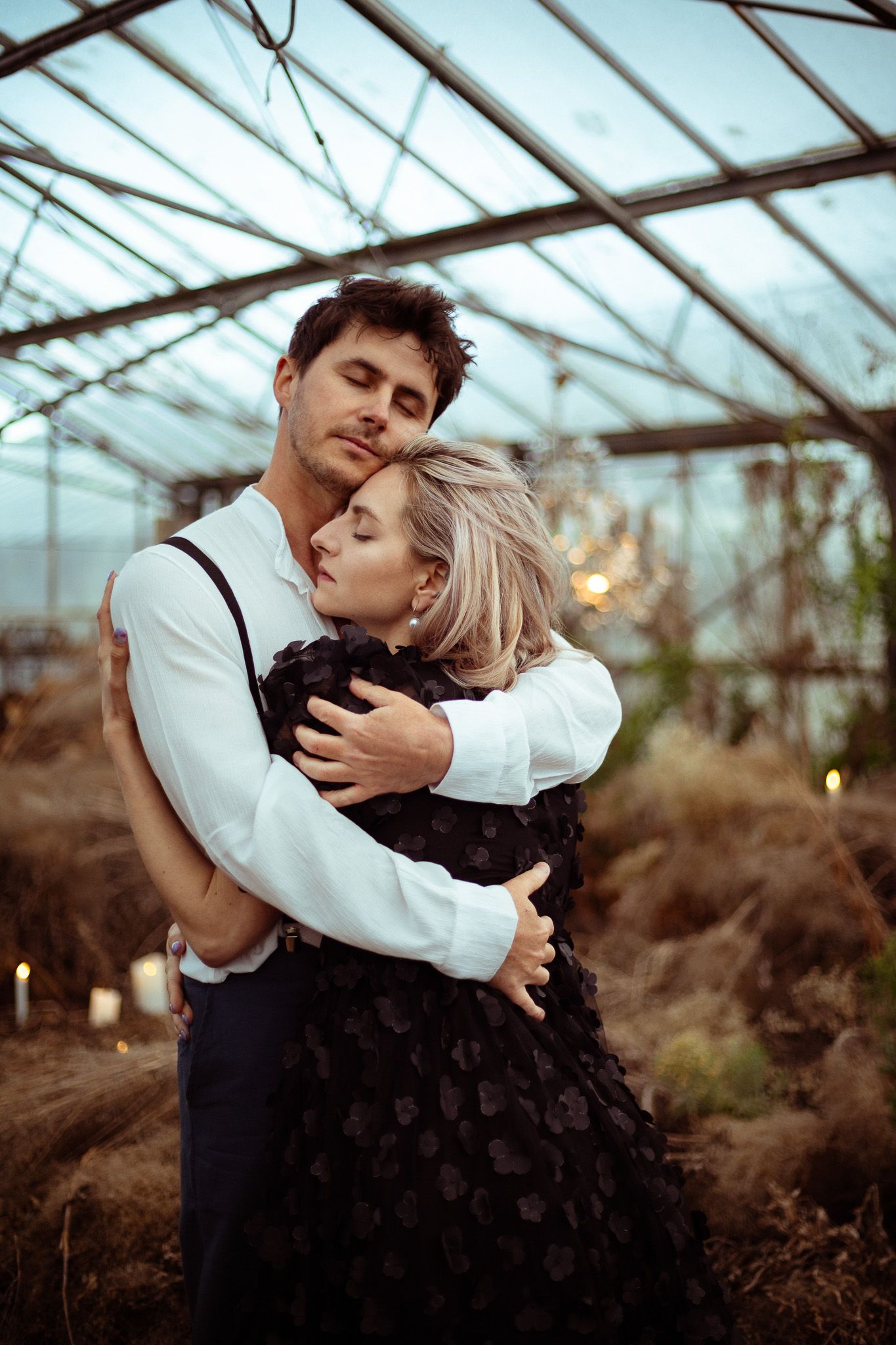 A tender embrace between two people in a greenhouse with natural lighting and rustic decor.
