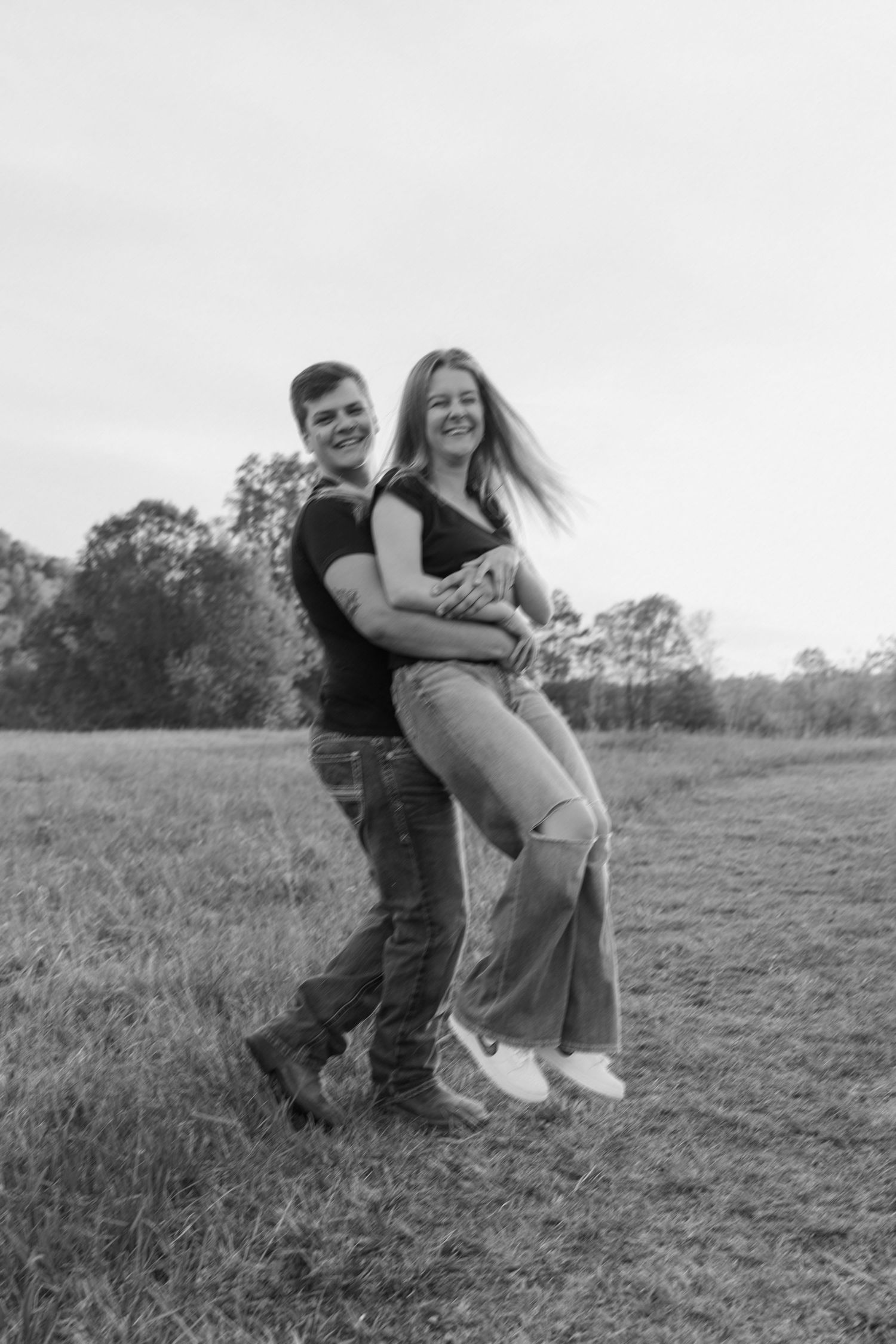 A black and white photo of a couple holding hands and walking together outdoors in a romantic moment.