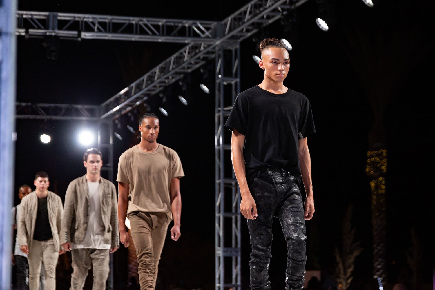 Fashion runway show with models walking in casual urban streetwear.