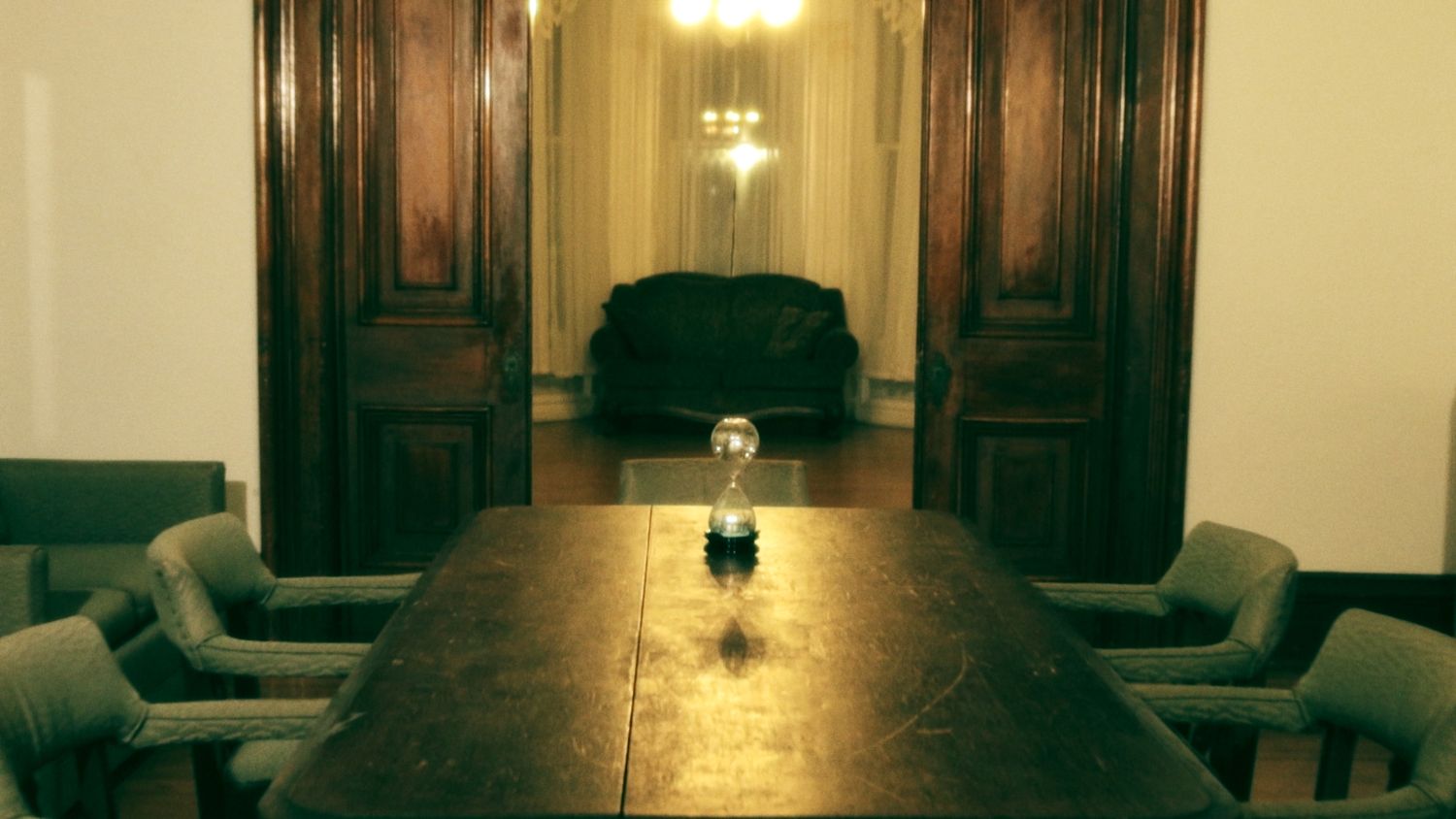Dark and moody long conference room with wooden table and empty chairs.
