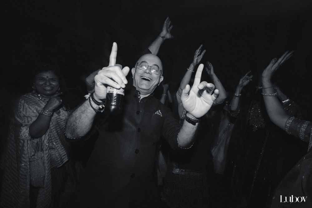 Celebration on a dance floor with guests gesturing and dancing in black and white photography.