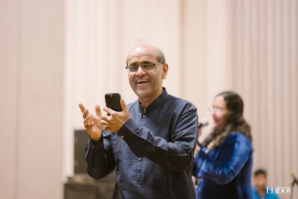 A person in a blue shirt holds up a mobile phone during an event.