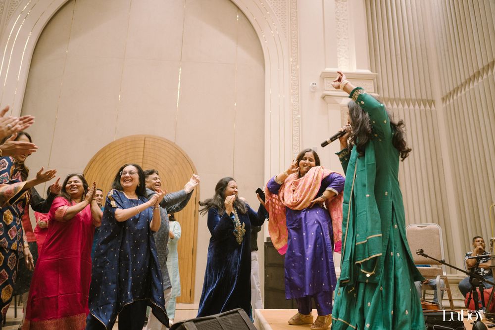Performers in colorful dresses dance and raise their arms on stage.
